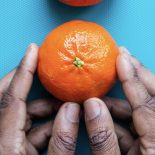 Mãos pegam em laranja